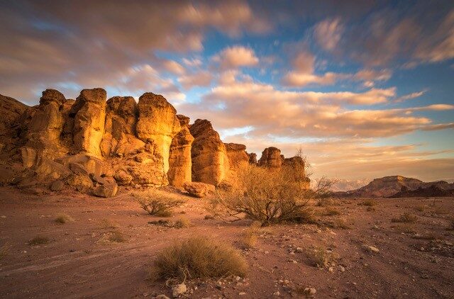 A desert landscape with rocks and clouds in the sky.