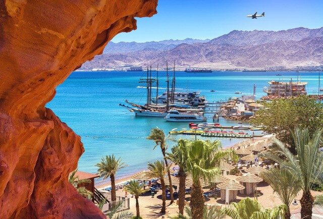 A beach with palm trees and boats in the water.