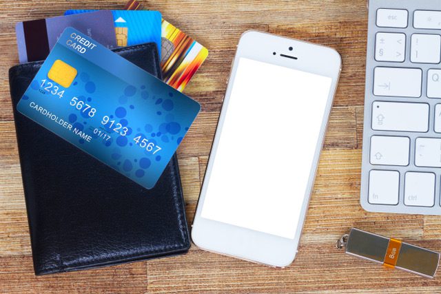 A wallet, phone and credit cards on a table.