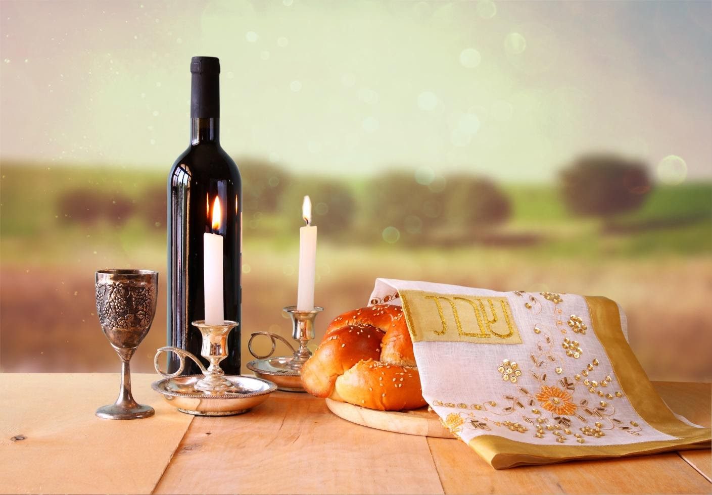 A table with wine, bread and candles on it.