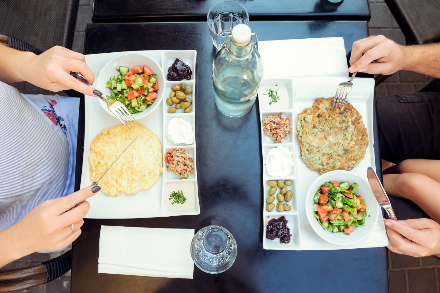 A couple of people sitting at a table with plates of food.